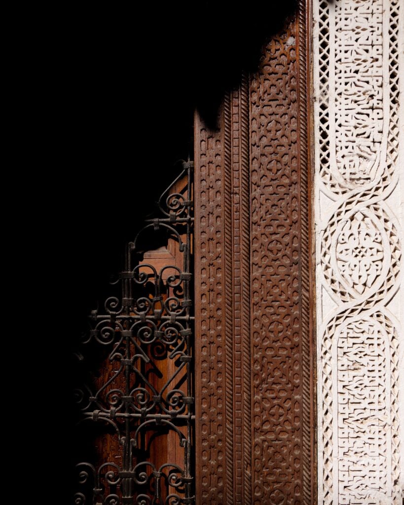 A carved cedar door in dramatic light and shadow at El Fenn, Marrakech.