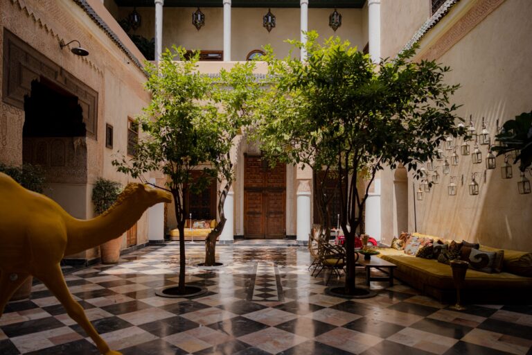 The tree-filled central courtyard of El Fenn, Marrakech, with tiled floors and low seating.