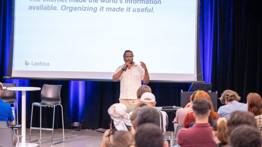 The Record Is the Asset 2 Chris Emezue, founder of Lanfrica, presenting in Montréal in front of a slide about organising information.