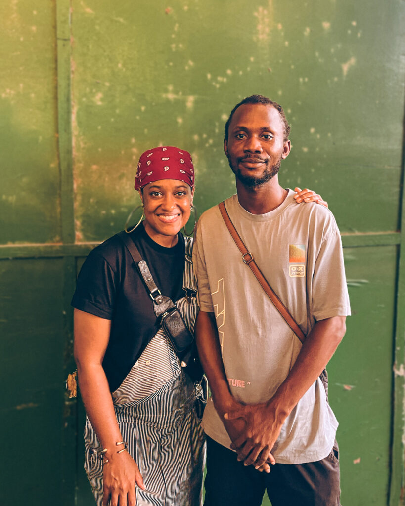Before the Album, Rapsody Went to Ghana 1 Rapsody and director Joseph Amino stand together against a weathered green wall during the filming of “Rapsody in Ghana.”