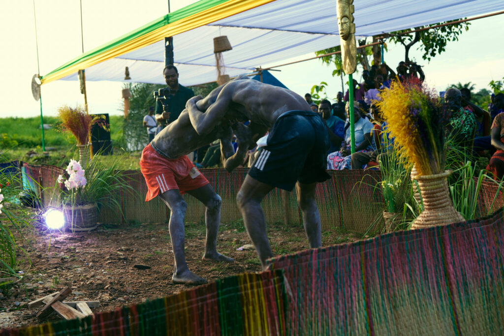Heal by Hair: How Communities, Culture, and Trust Are Redefining Mental Health Across Africa 4 Two Togolese Évala wrestlers grapple inside a matted arena as spectators look on at the Heal by Hair Festival in Siou, Togo