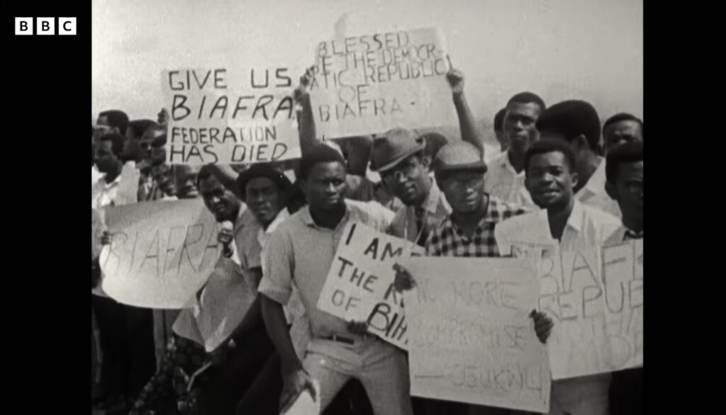 Demonstrators holding hand-lettered placards reading Give Us Biafra and Federation Has Died, in BBC archive footage of the 1967 push for secession in eastern Nigeria.