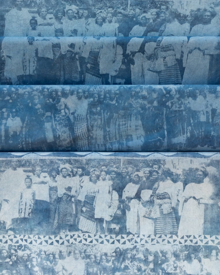 Detail of indigo-dyed cloth layered with pale archival photographs of Nigerian women in wrappers and head ties.