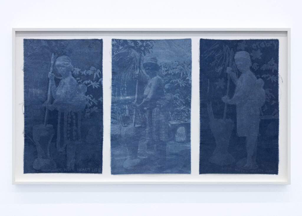 Adirẹ and the Wrapper-Wearers 4 A framed triptych of three indigo cloth panels, each showing a faint figure pounding cassava with a long pestle among tropical foliage.