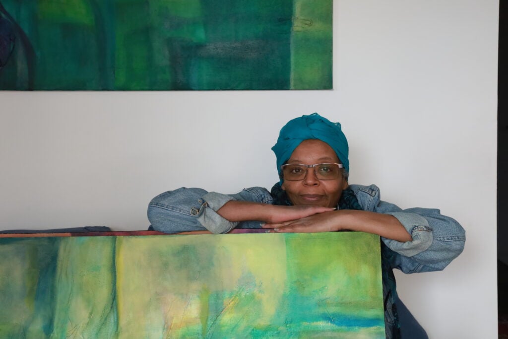 Portrait of Sudanese painter Aisha Hussein Shariffe with one of her paintings