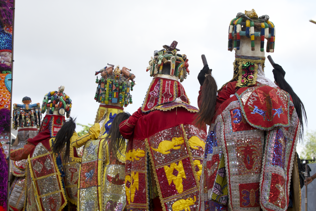 Rear view of Egungun masquerades showing carved wooden superstructures crowded with figures and animals