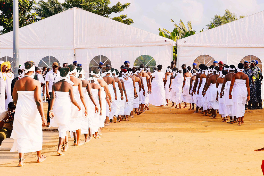 Women dressed in white walking between festival tents before the procession begins