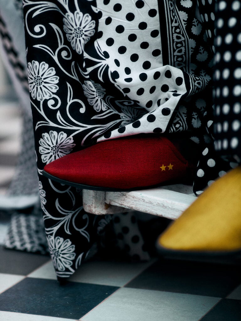 City Codes: Dakar Is Not a Trend 4 A detail of black-and-white floral and polka-dot boubou fabric draped over a white bench with a deep-red, star-embossed cushion.