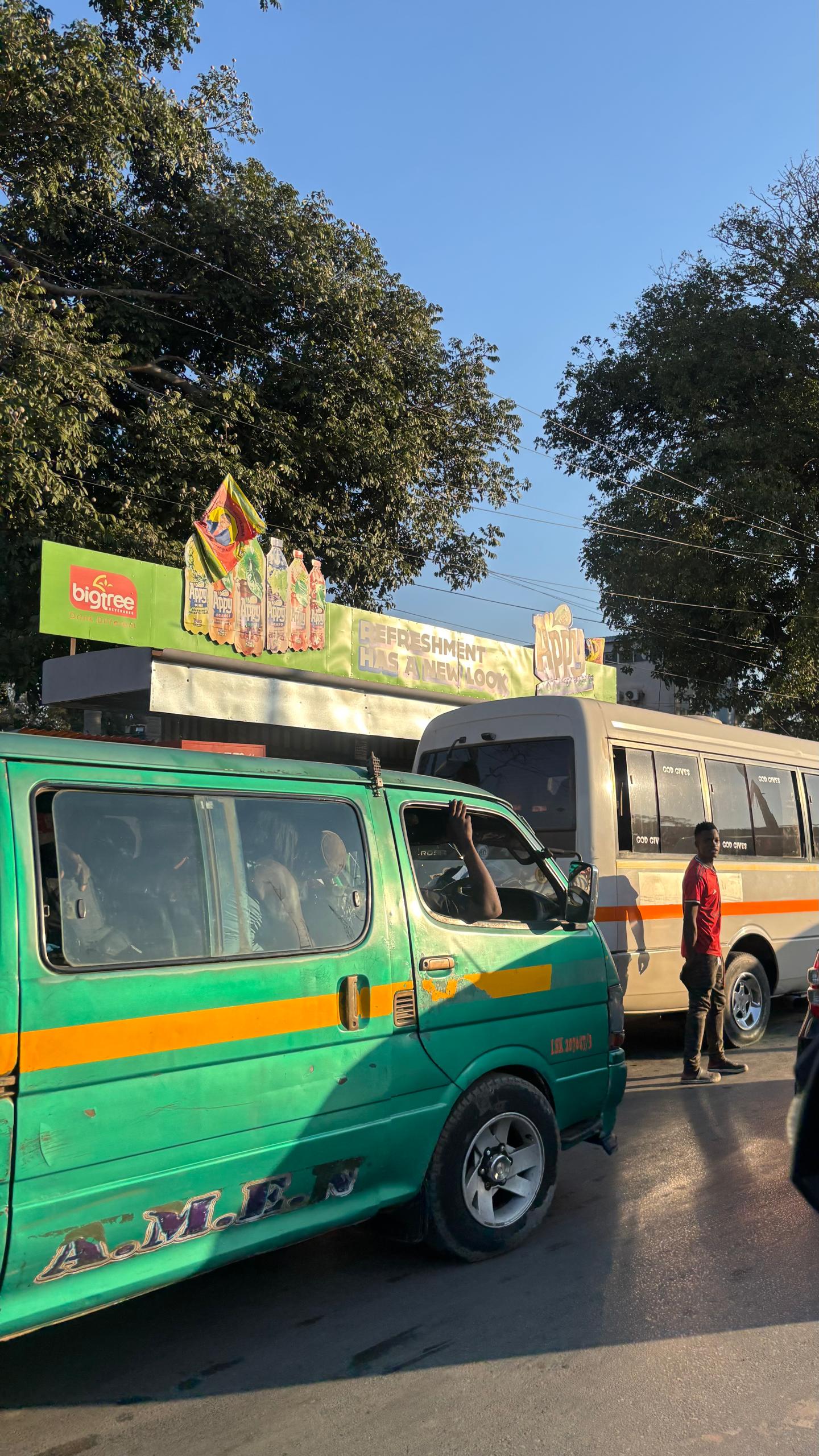 How Lusaka Moves 11 Commuters at a covered bus stop on a street in Lusaka.