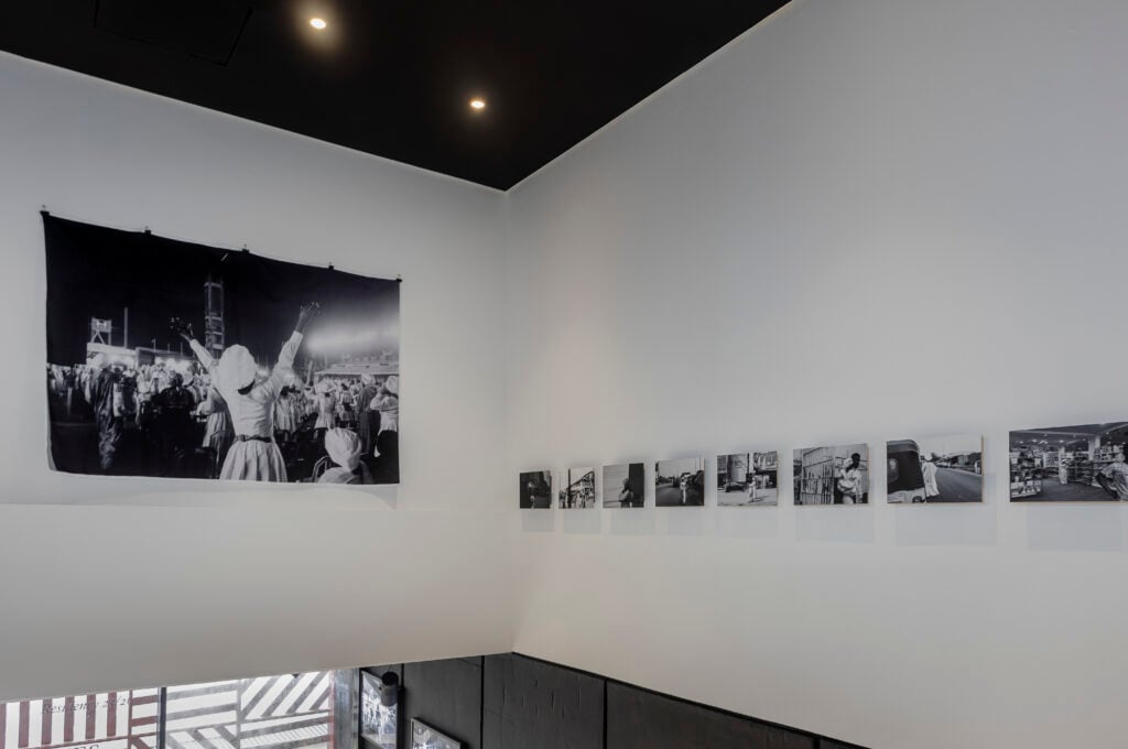 Holy Dress Codes: What Comes to Mind When You See the Garment? 5 Installation view of Stephen Tayo's exhibition at Alara Lagos, a large unframed print of a worshipper with raised arms beside a row of smaller prints.
