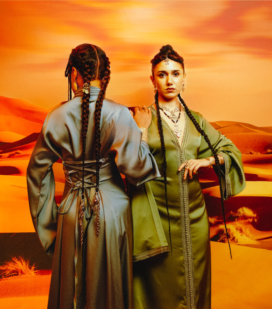 North African Women Wore the Future First 4 Two models in green YSR Maison velvet gowns and Tausa World jewellery, standing against an orange desert landscape.