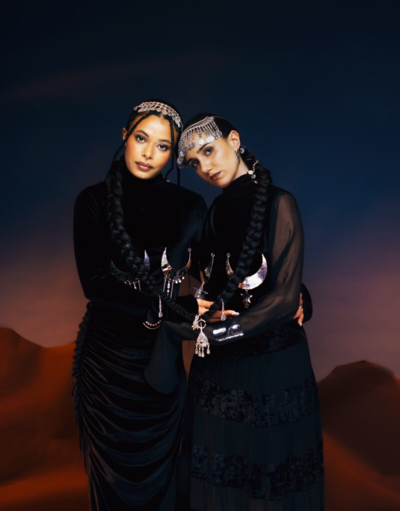 North African Women Wore the Future First 7 Two models in black Ruaa Elmansuri looks with silver Tausa World jewellery, photographed together at dusk in the desert.