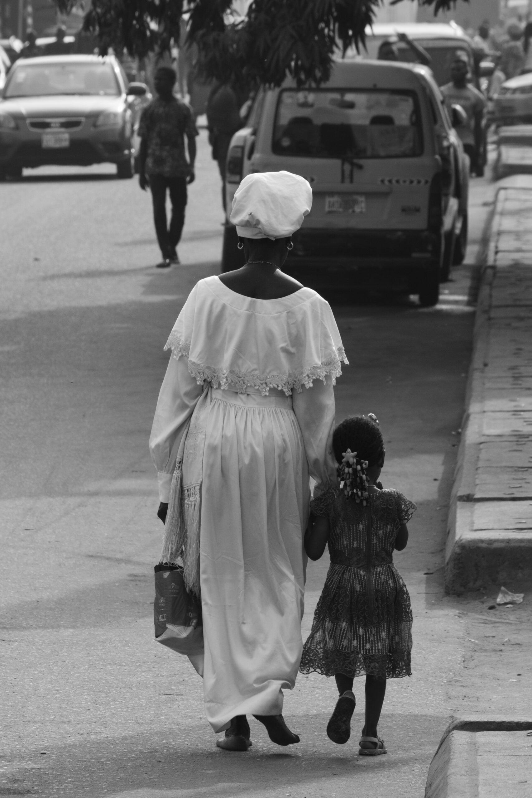 Holy Dress Codes: What Comes to Mind When You See the Garment? 9 A worshipper in a white Aladura garment sits alone on a concrete stairway behind metal railings, in black and white by Stephen Tayo.