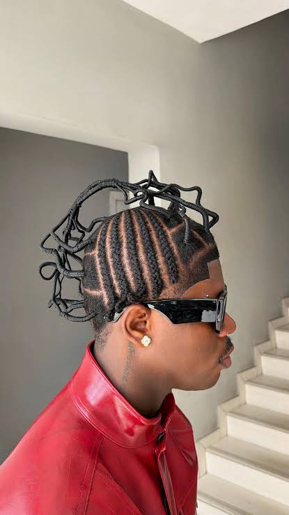 The Art of African Braiding, Through the Eyes of Gen Z 2 Side view of Emeka Onyeziri with cornrows and an open, looped threaded hairstyle, wearing sunglasses and a red jacket.