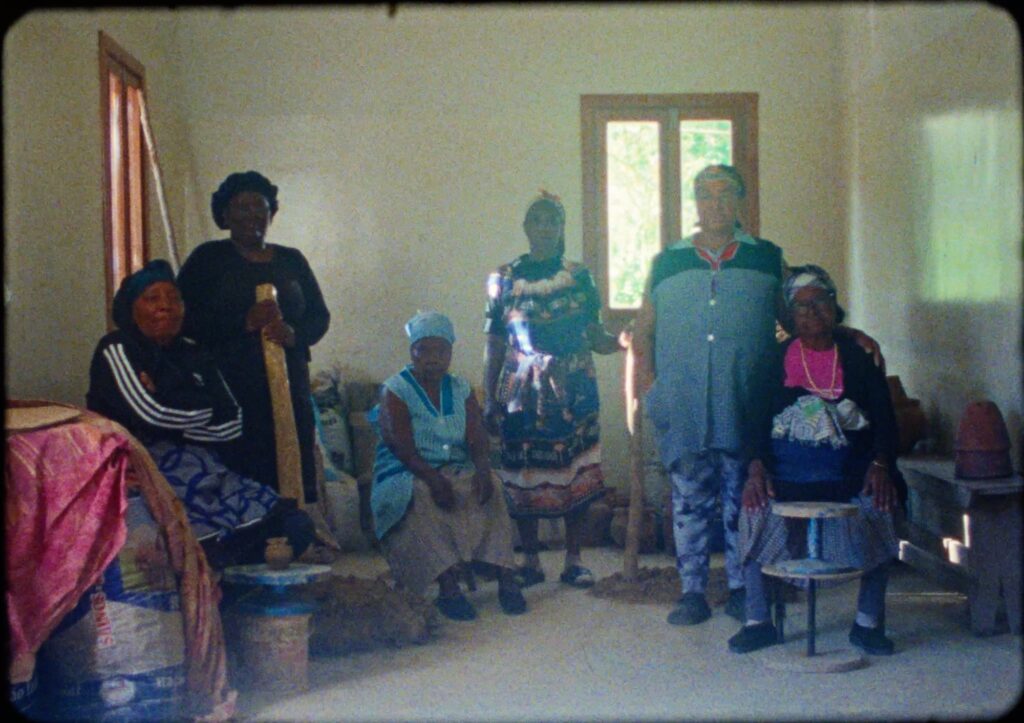 A group of women potters in a whitewashed workshop on Santiago, Cape Verde, some seated beside low wooden turntables, in a still from Filhas do Barro.