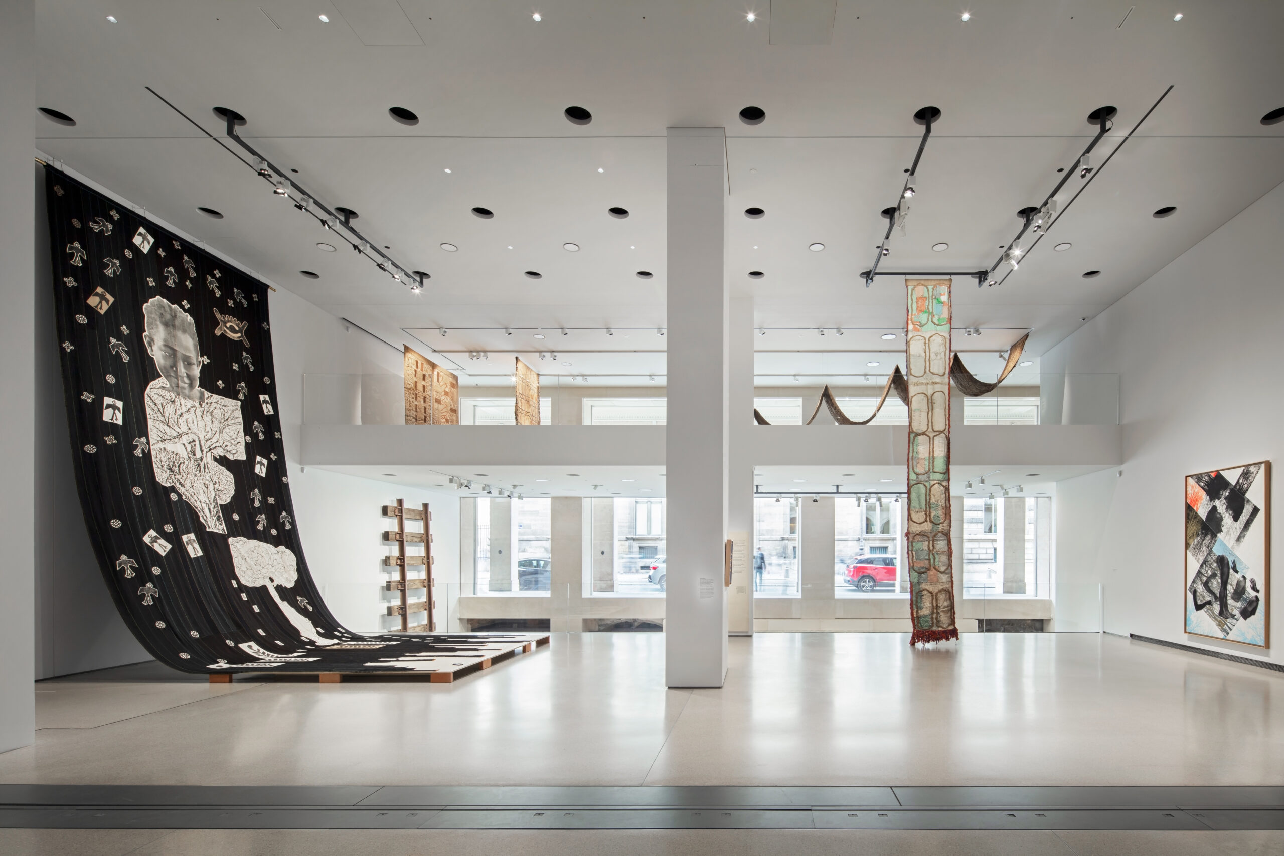 Ibrahim Mahama Brings Ghana's Industrial Past to Paris 3 Large textile works hang from the ceiling and extend towards the floor in a bright gallery at Fondation Cartier.
