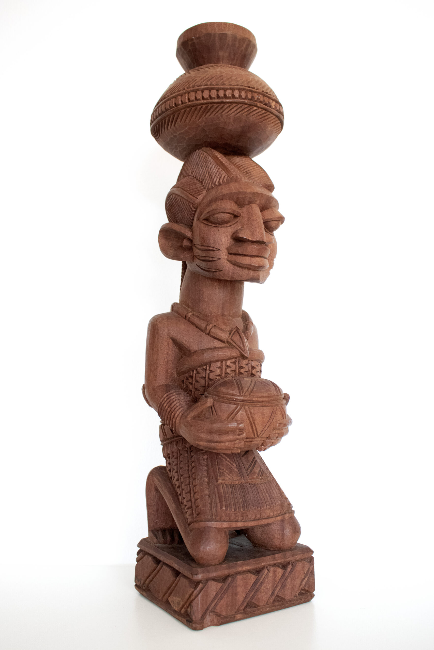 Lamidi Olonade Fakeye’s carved wooden Mother and Child sculpture, showing a kneeling woman holding a vessel with a child on her back.