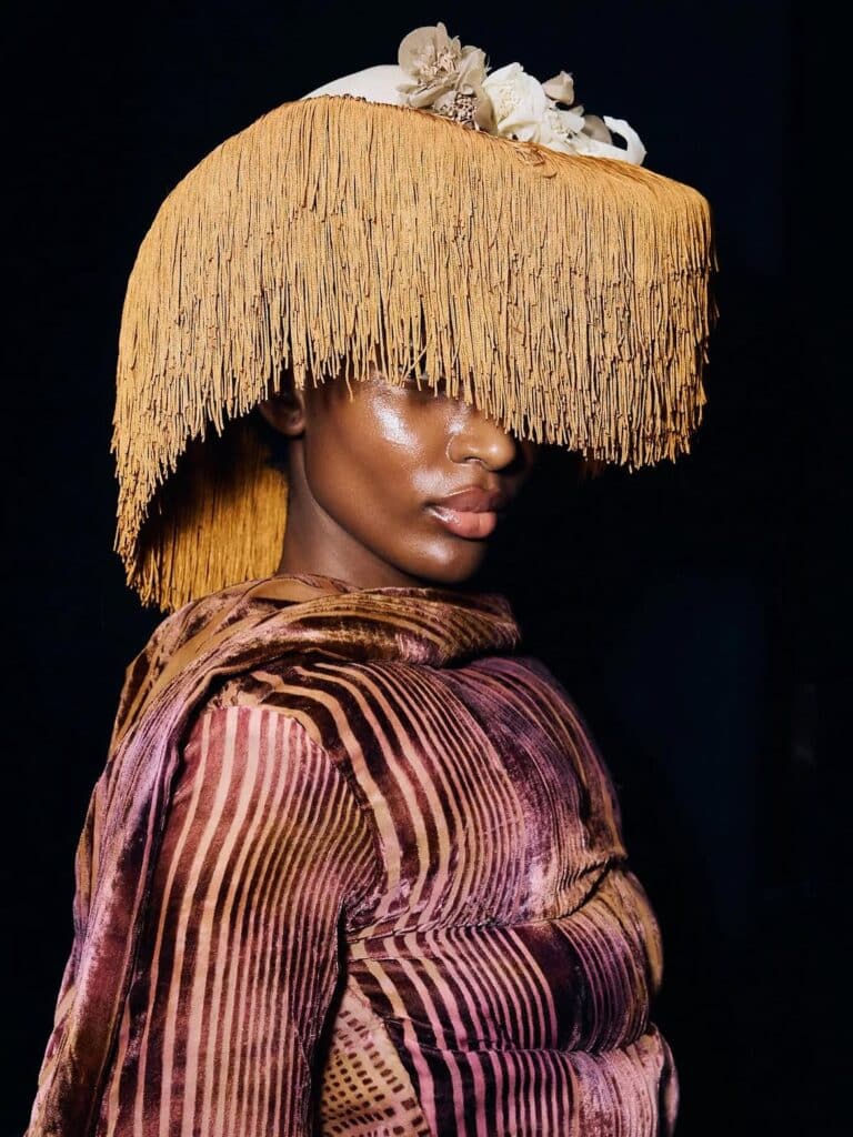 Dede Arisekola Is Building a World of Her Own 4 Holy One model wearing a sculpted striped top and fringed headwear backstage