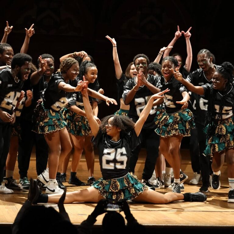 Members of Harvard’s Omo Naija x Wahala Boys perform in matching green and yellow print uniforms.