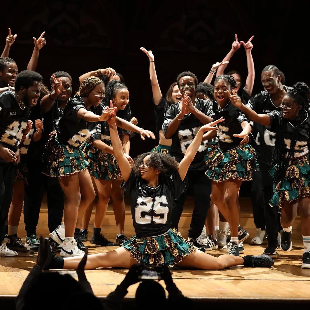 Members of Harvard’s Omo Naija x Wahala Boys perform in matching green and yellow print uniforms.